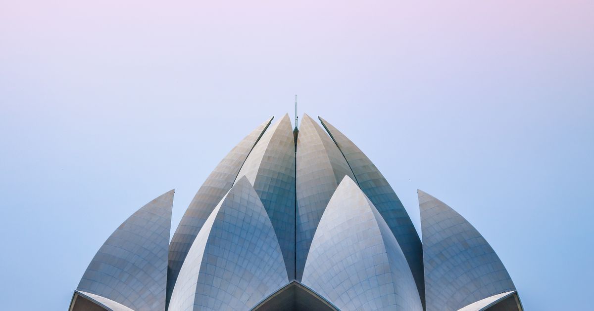 Overlapping white petal-shaped roof panels of the Lotus Temple rising against a pale sky
