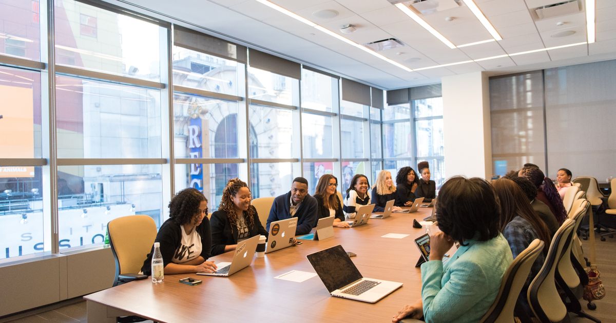 A sales team working on laptops around a long boardroom table, the kind of team that builds prospect lists from LinkedIn