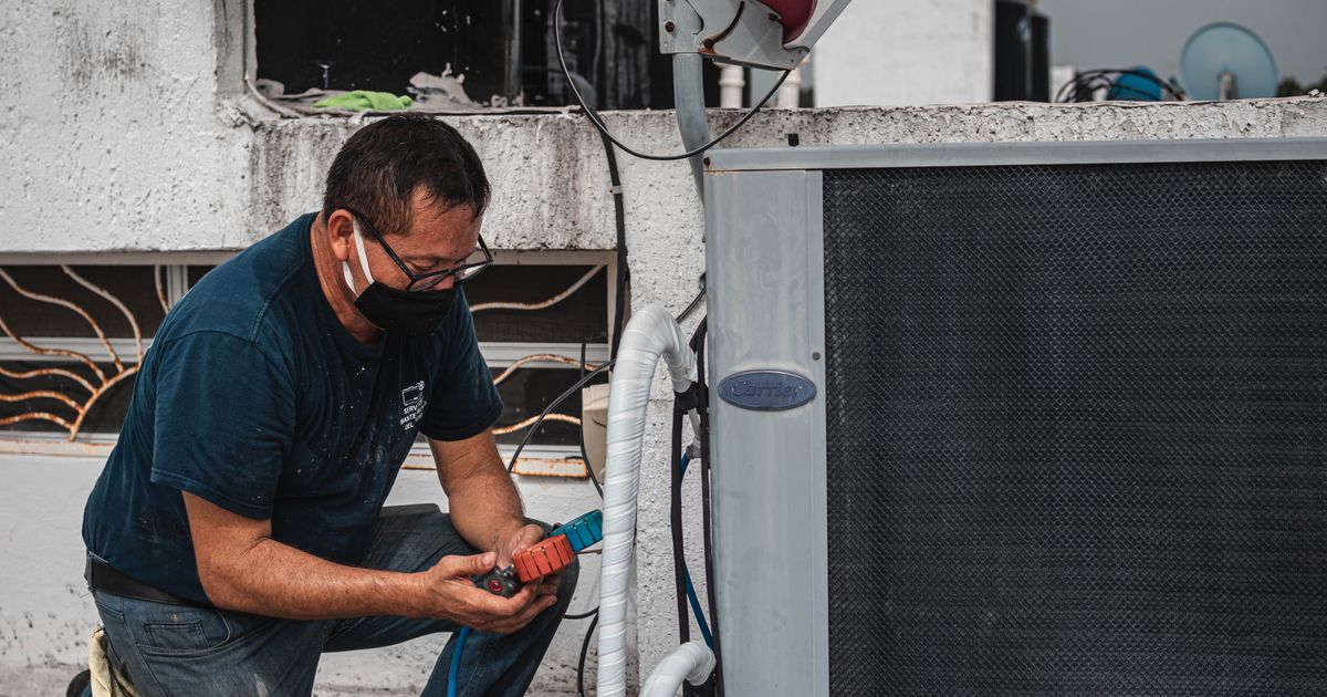 An HVAC technician servicing a commercial rooftop air-conditioning unit